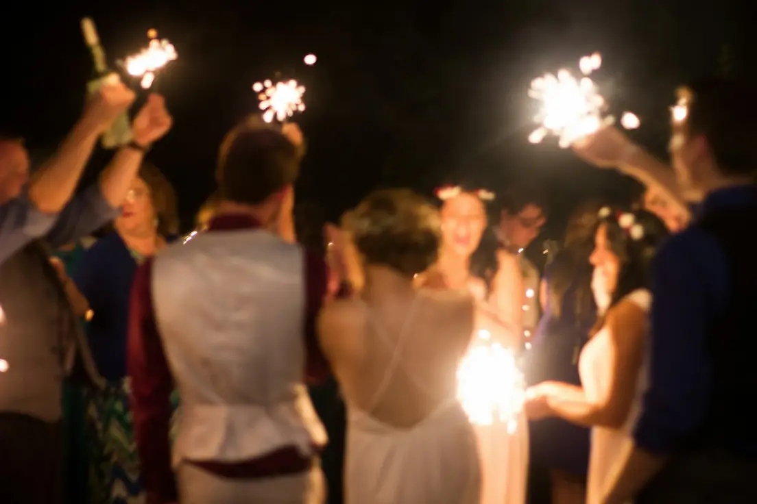 Guests gathered outdoors at night facing warm stage lights